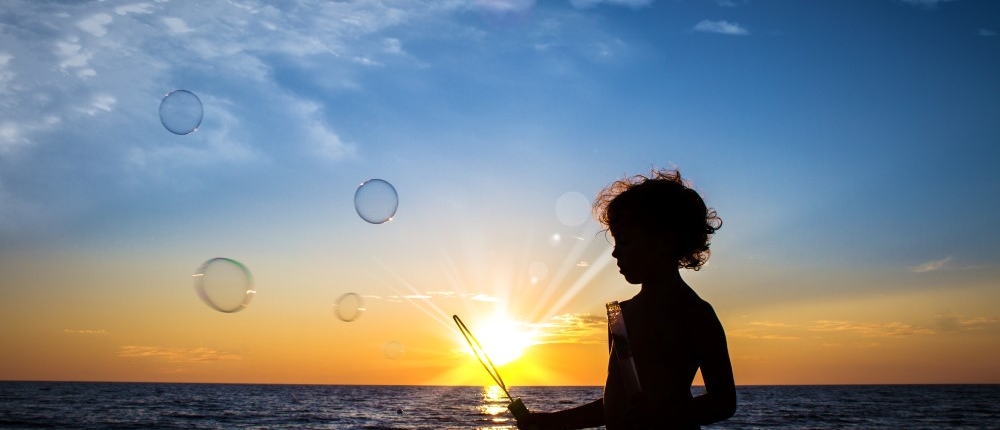 A boy plays on the beach at sunset.